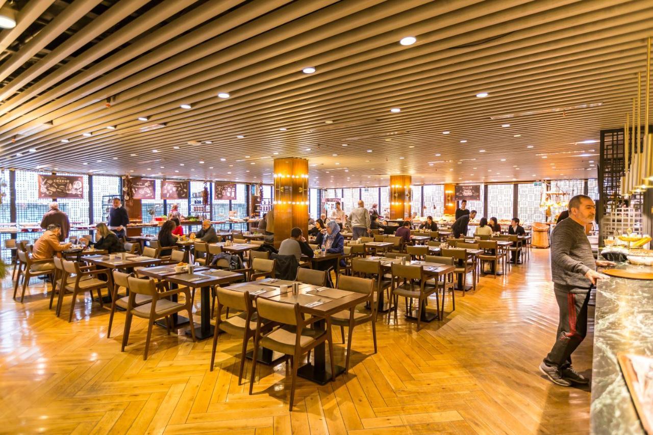 Sura Hagia Sophia Hotel Истанбул Екстериор снимка The photo depicts a modern restaurant interior filled with people dining. The space features wooden flooring and overhead beams, creating a warm and inviting atmosphere. Tables are arranged with chairs, and various diners are seen interacting and enj