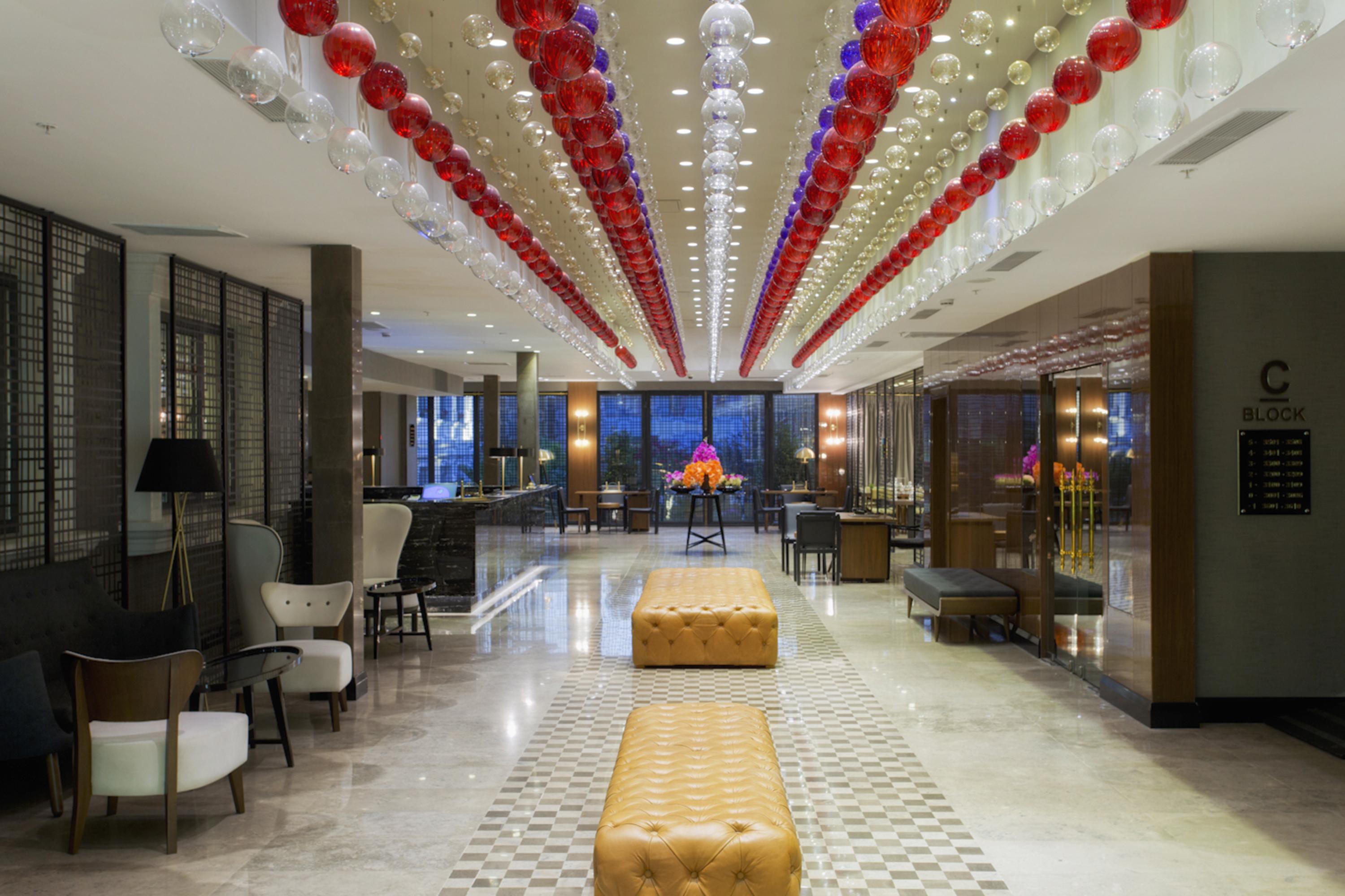 Sura Hagia Sophia Hotel Истанбул Екстериор снимка The photo shows a modern hotel lobby featuring a stylish and elegant design. The ceiling is adorned with a series of colorful hanging decorations, predominantly in red, white, and blue, creating a festive atmosphere. The floor is made of polished mar