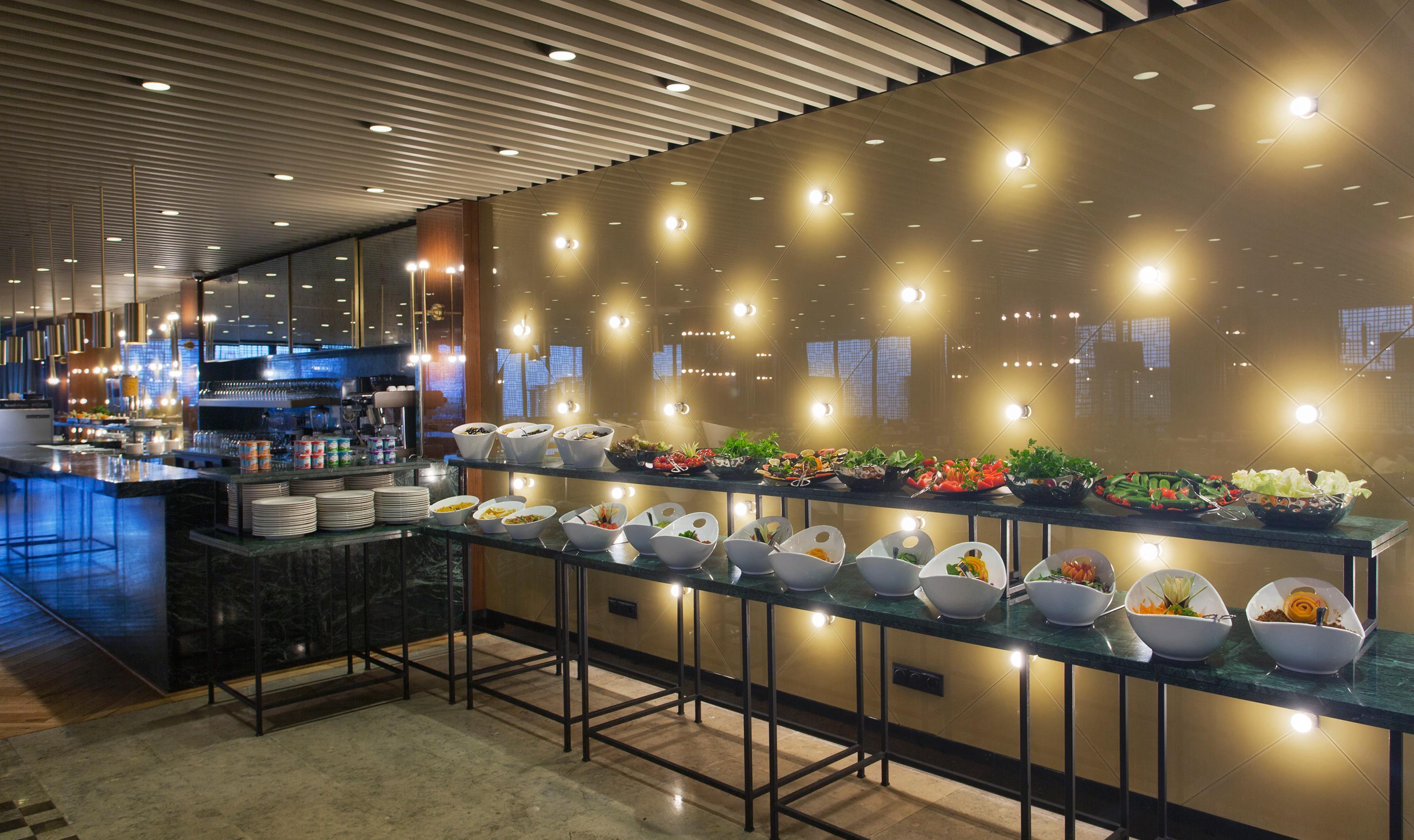 Sura Hagia Sophia Hotel Истанбул Екстериор снимка The photo depicts a buffet setup in a modern restaurant or dining area. There are multiple long tables displaying an array of food items in various bowls. The dishes appear to include salads and other colorful offerings, neatly arranged for guests. T