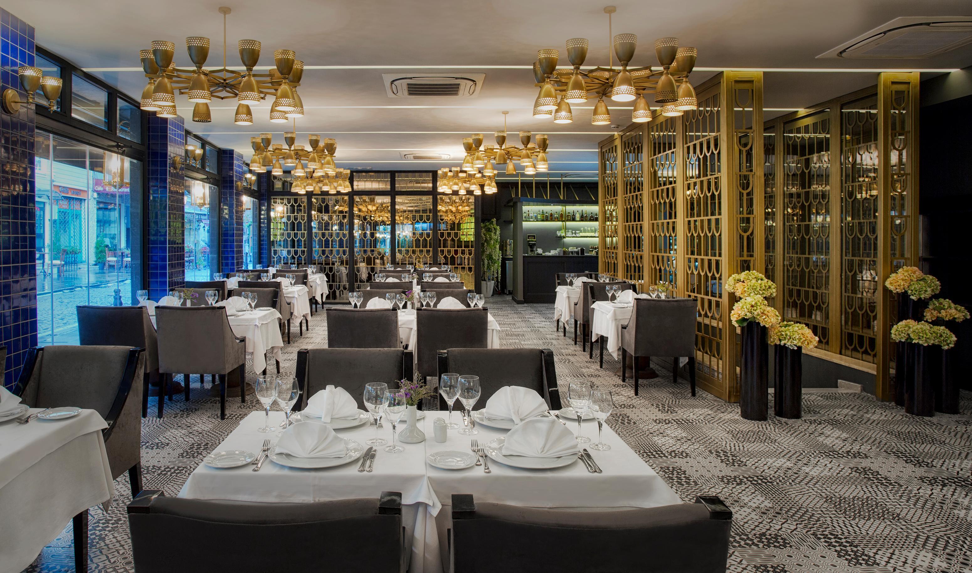 Sura Hagia Sophia Hotel Истанбул Екстериор снимка The photo shows the interior of a modern restaurant. It features a spacious dining area with elegantly set tables covered in white tablecloths. Each table is arranged with fine dining utensils and glassware. The restaurant has a contemporary design, 