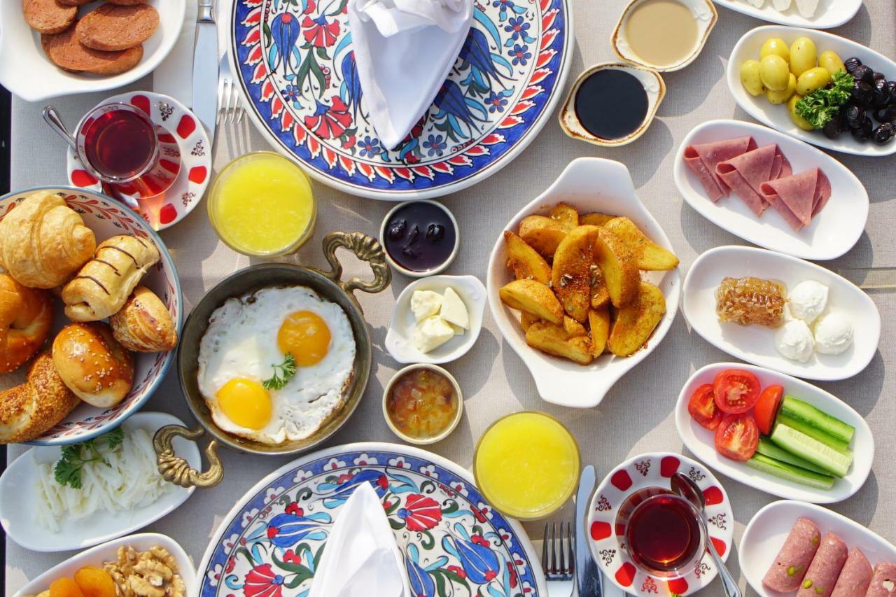 Sura Hagia Sophia Hotel Истанбул Екстериор снимка The photo displays a large spread of a breakfast table with various dishes arranged beautifully. In the center, there are two sunny-side-up eggs in a bowl. Surrounding this, there are items such as pastries (like croissants), slices of various types 